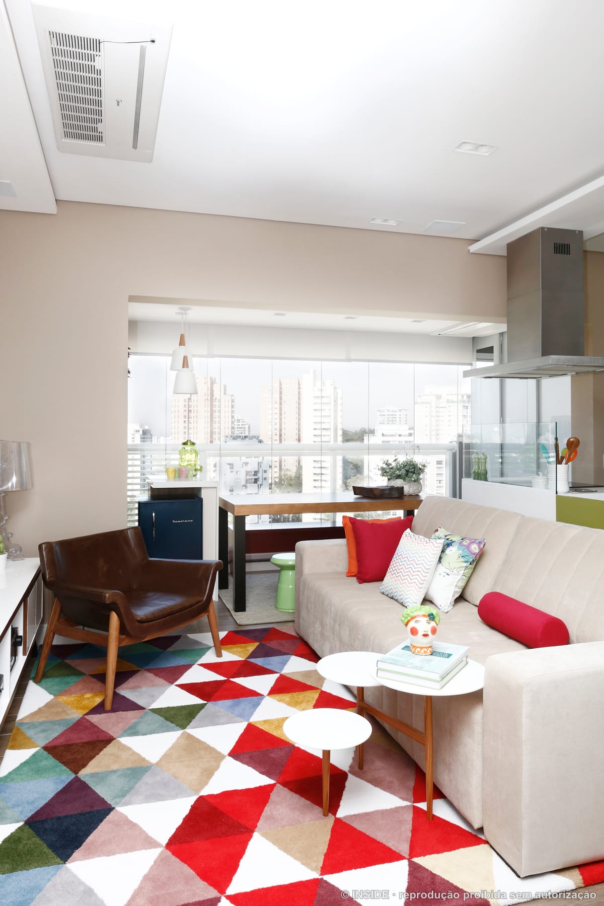 Sala e cozinha integradas com marcenaria em painéis coloridos, sofá claro e janela com vista da cidade, projeto INSIDE
