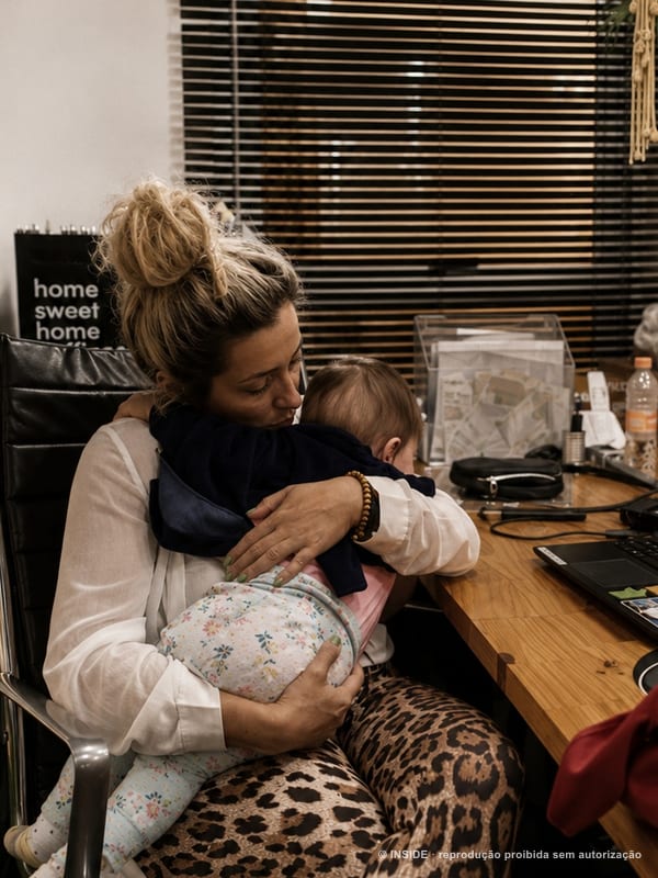 Sara Rollemberg com uma criança da família no colo, trabalhando no estúdio da INSIDE, 2022, acervo INSIDE