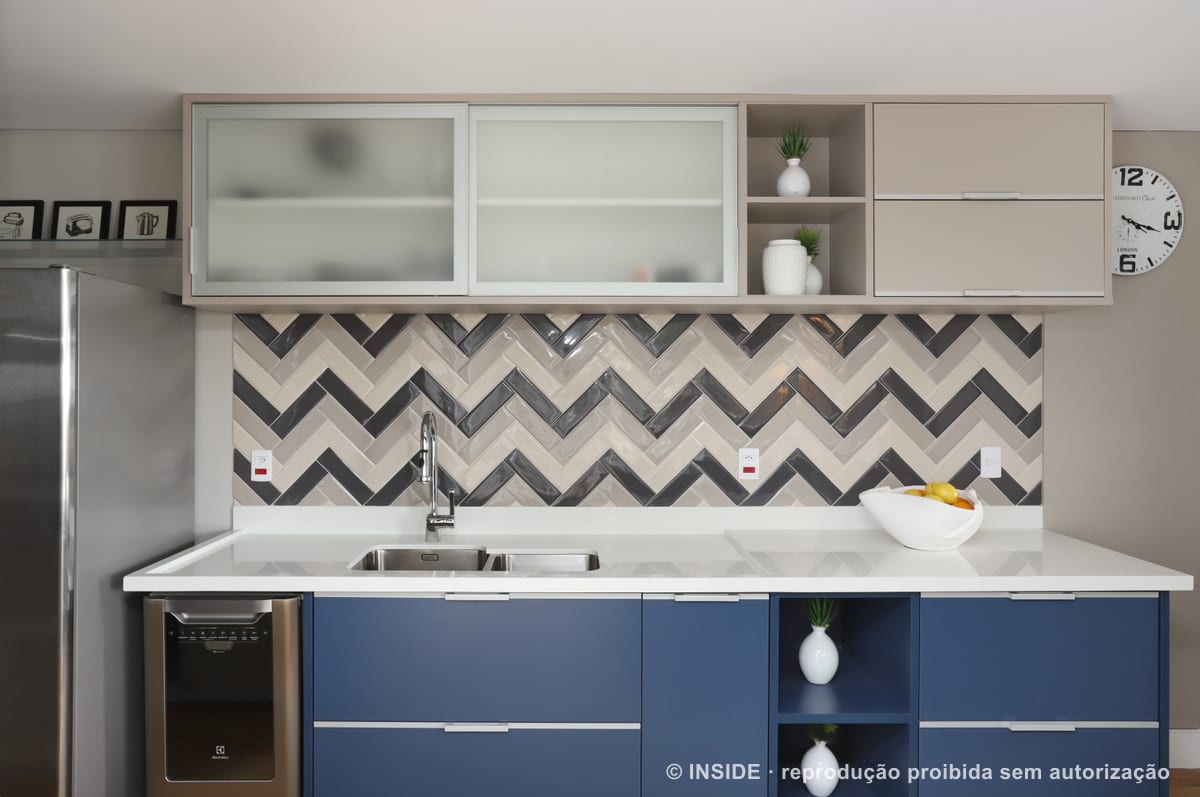 Cozinha com marcenaria azul-marinho, bancada branca e faixa de revestimento em espinha nos tons de cinza e branco, apartamento Brooklin-PE, foto Mariana Orsi, acervo INSIDE