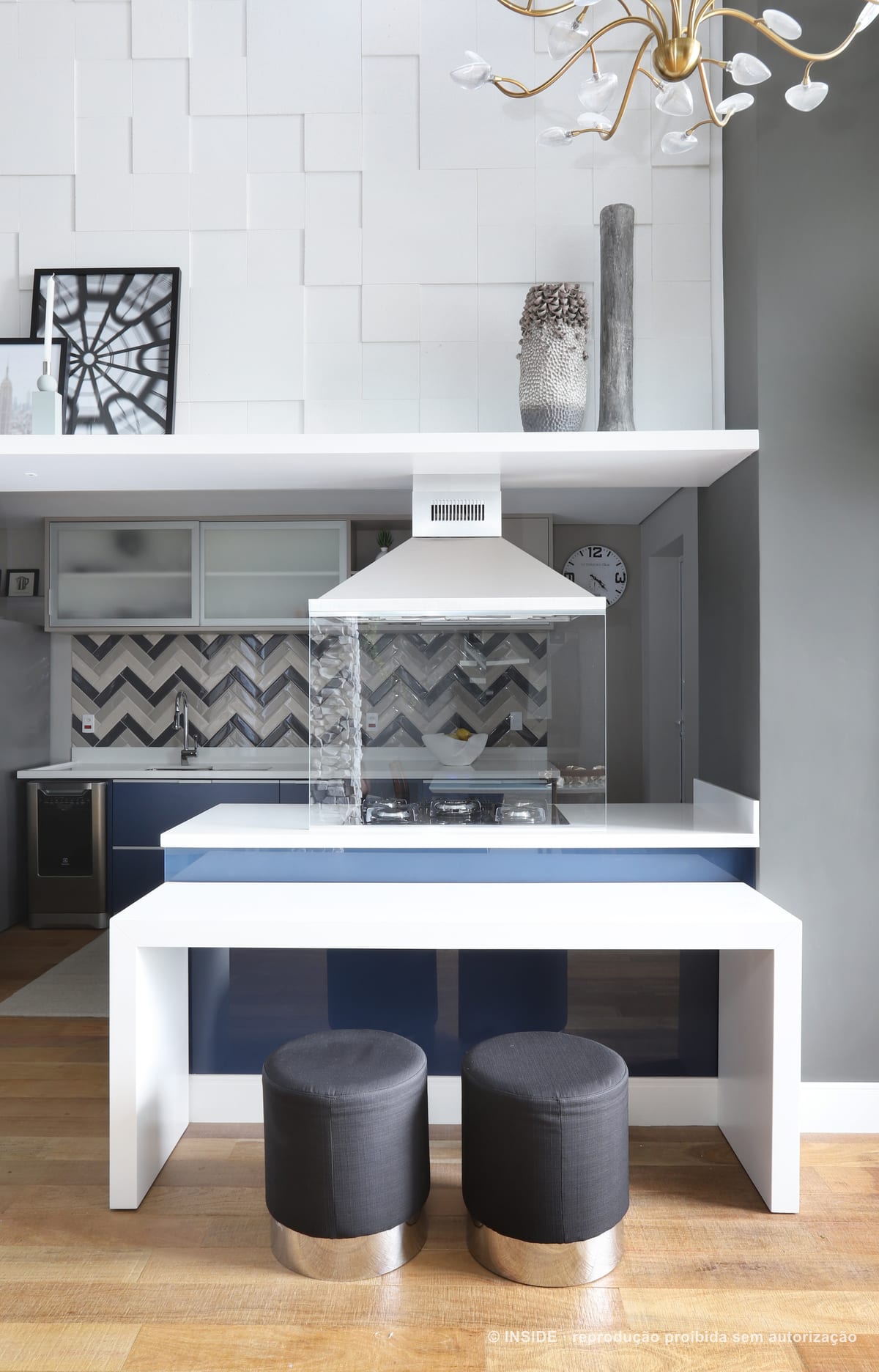 Ilha de cozinha com cooktop e coifa de inox, aberta para a sala, com armários azuis e revestimento em espinha ao fundo, apartamento Brooklin-PE, foto Mariana Orsi, acervo INSIDE