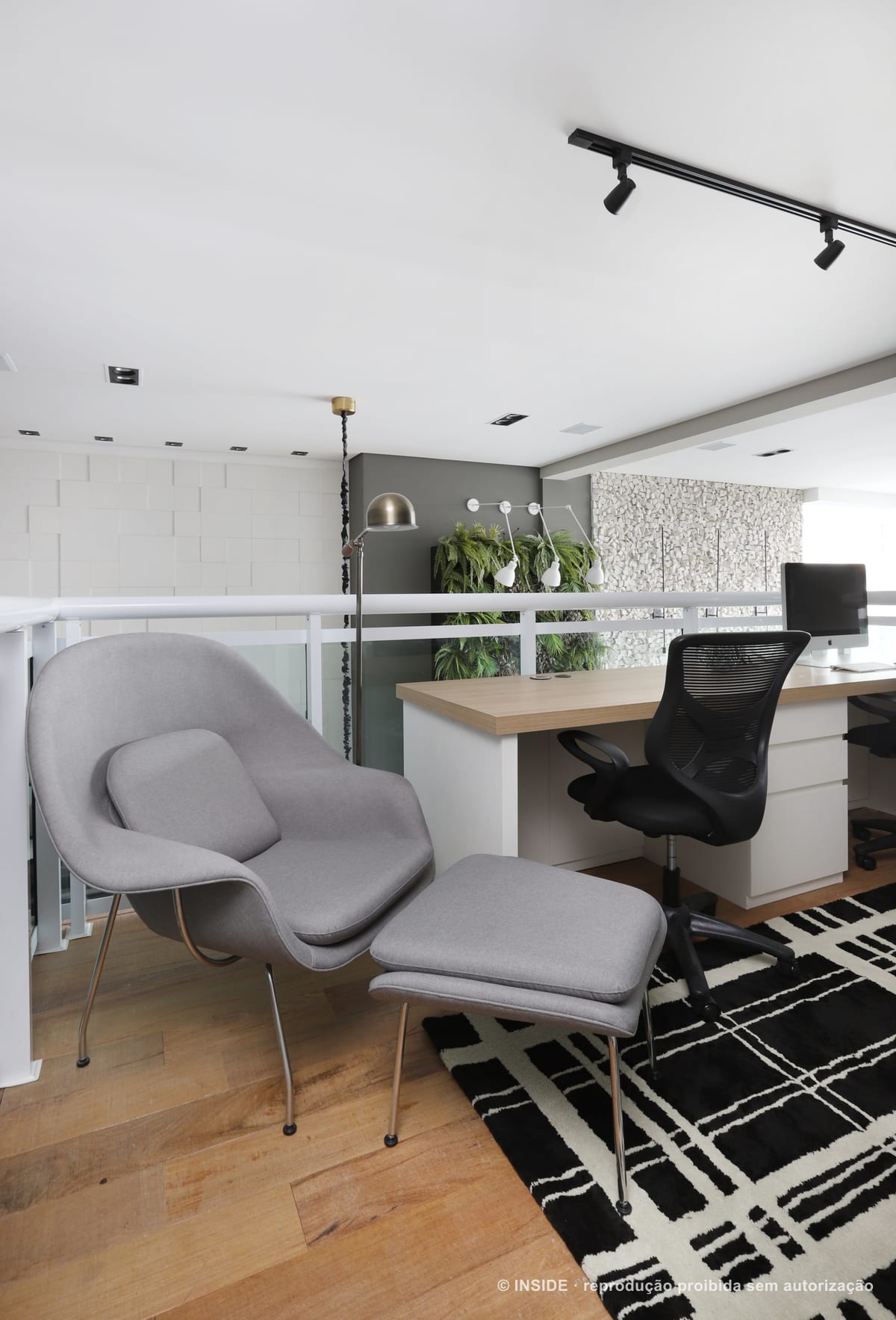 Home office no mezanino com poltrona Womb cinza e pufe, bancada de madeira, cadeira de escritório e guarda-corpo de vidro sobre a sala, apartamento Brooklin-PE, foto Mariana Orsi, acervo INSIDE