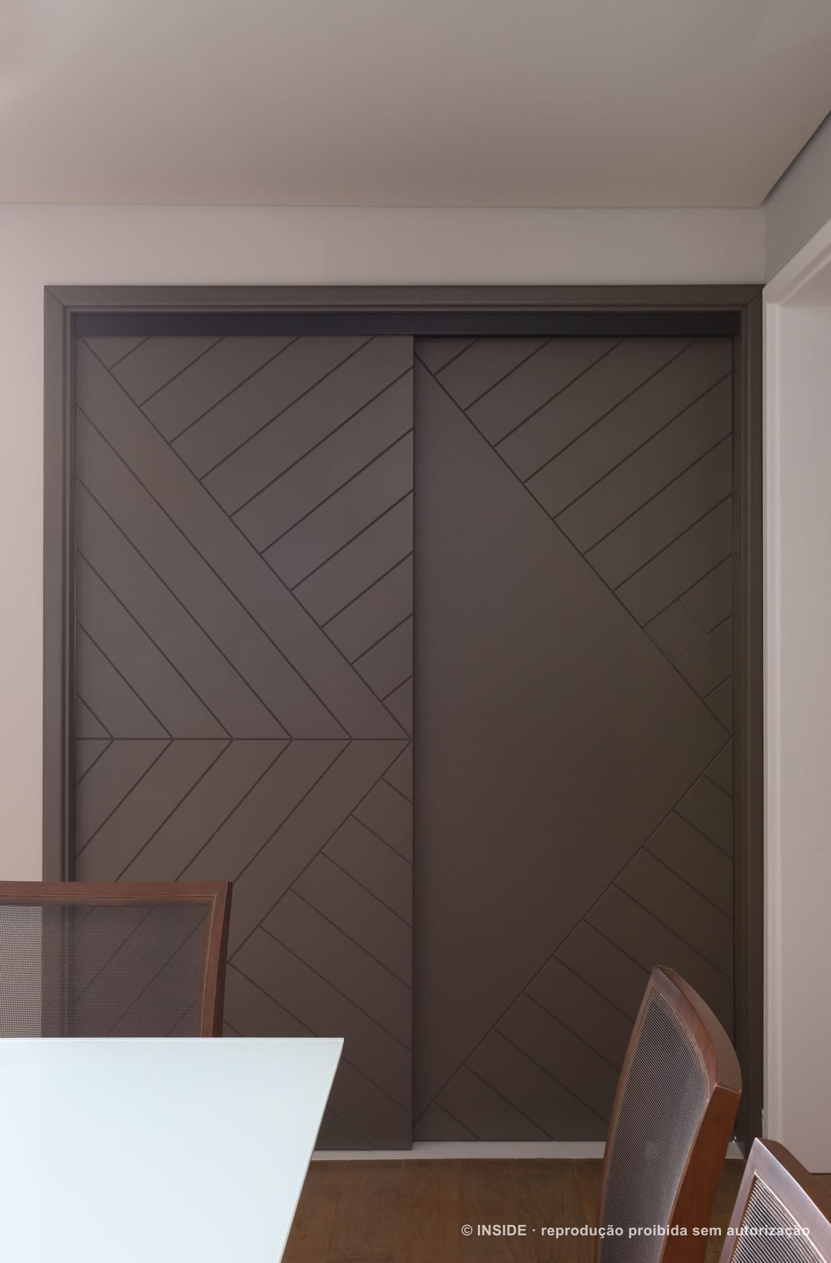 Porta de correr de marcenaria marrom com desenho em espinha e nenhum puxador aparente, apartamento Brooklin-PE, foto Mariana Orsi, acervo INSIDE