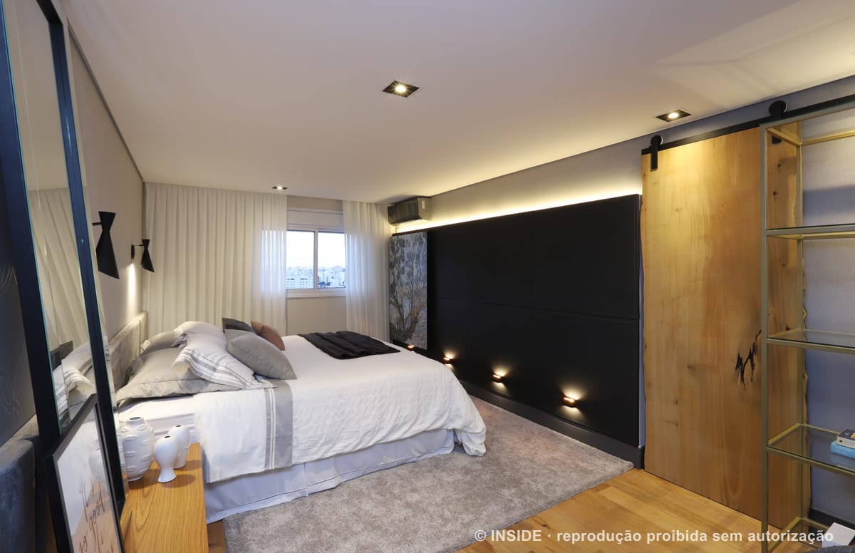 Suíte do casal com cabeceira estofada, faixa de luz rasante junto ao piso, espelho de chão e porta de correr de madeira maciça, apartamento Brooklin-PE, foto Mariana Orsi, acervo INSIDE