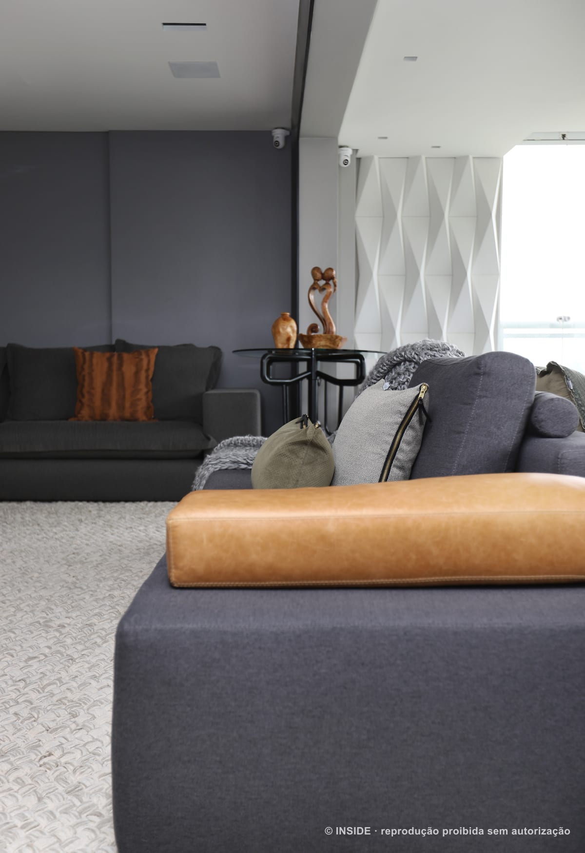 Canto do estar com chaise de couro caramelo, sofá cinza, painel geométrico branco e mesa lateral escura, apartamento Perdizes-DB, foto Mariana Orsi, acervo INSIDE