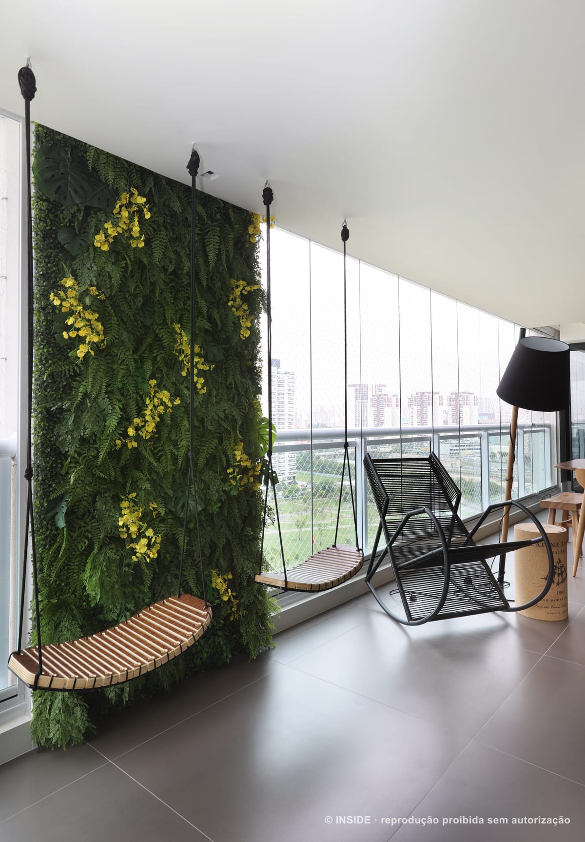 Parede inteira de jardim vertical com flores amarelas na varanda, ao lado de balanço de fibra e vista da cidade, apartamento Perdizes-DB, foto Mariana Orsi, acervo INSIDE