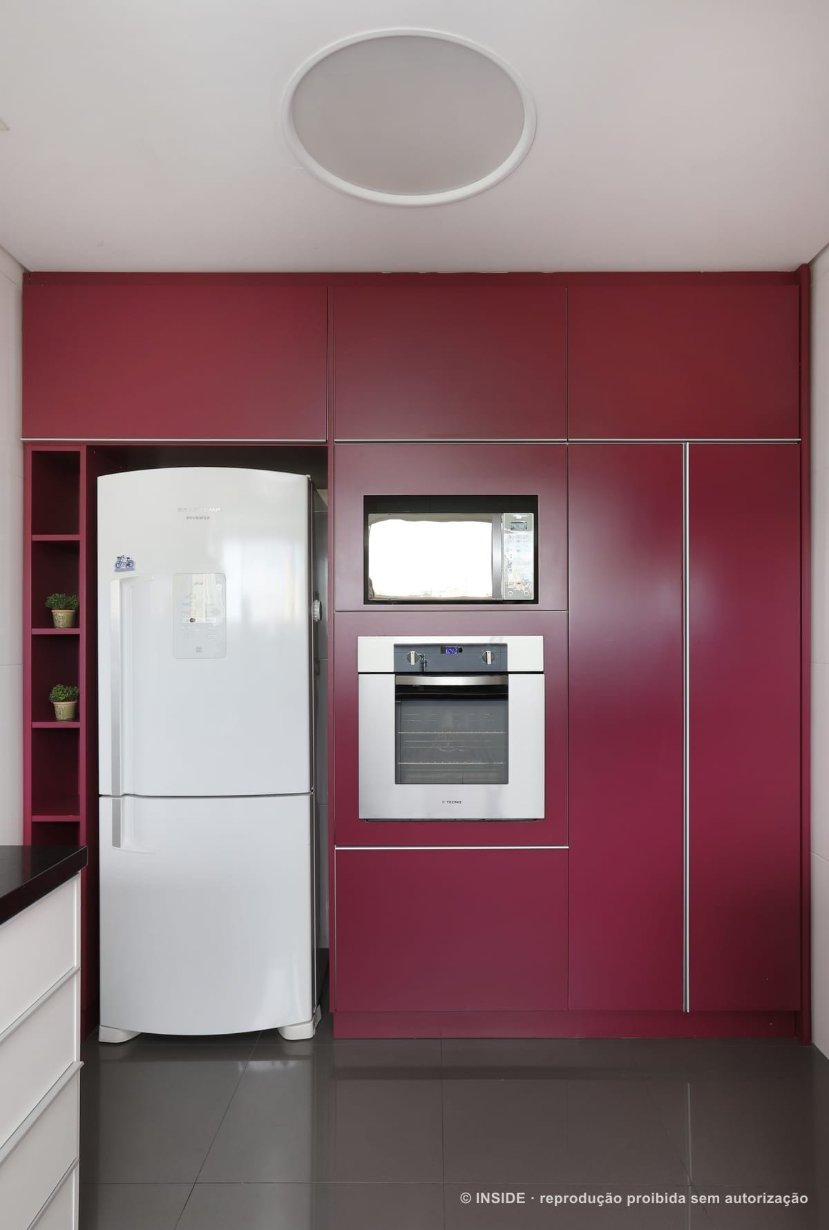 Parede da cozinha em laca magenta, com geladeira e forno embutidos e nicho lateral aberto, Vila Monumento-FC, foto Mariana Orsi, acervo INSIDE