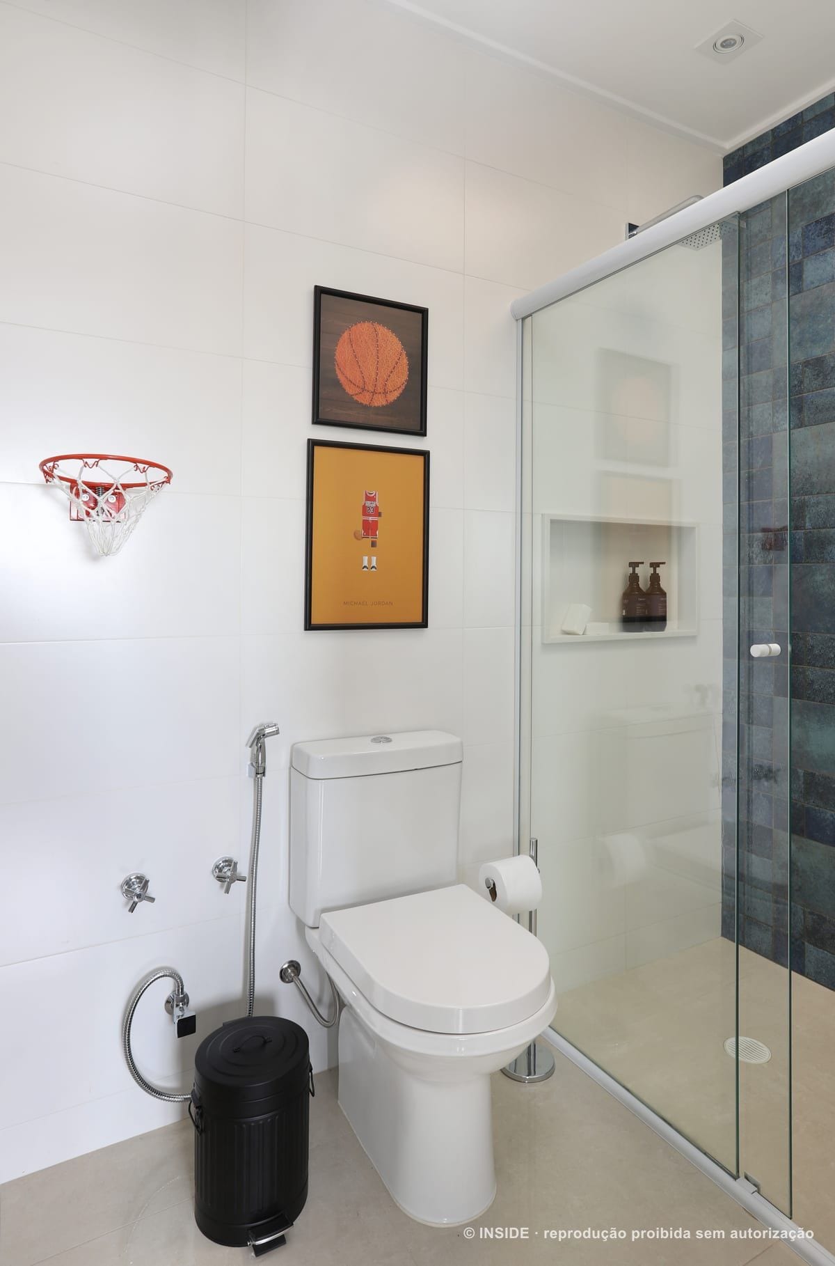Banheiro do menino com tabela de basquete instalada na parede acima do vaso, quadros de basquete e revestimento branco, Vila Monumento-FC, foto Mariana Orsi, acervo INSIDE