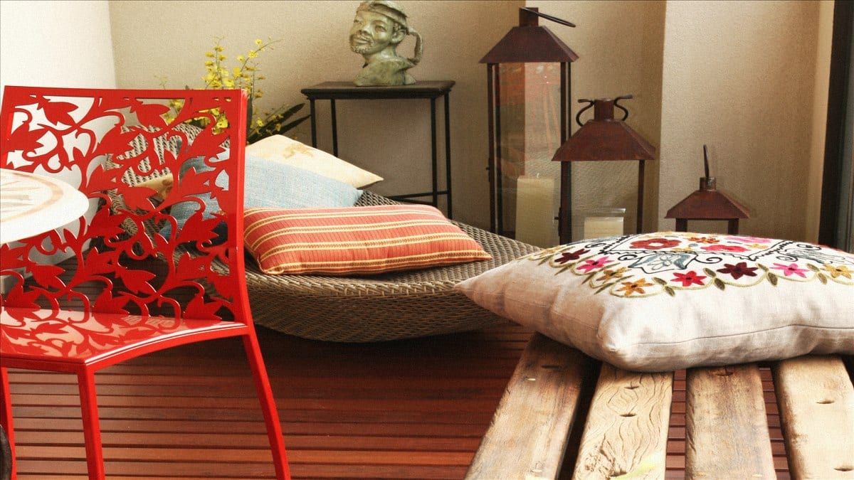 Varanda decorada com cadeira vermelha, almofadas bordadas e lanternas - tudo transportável, projeto INSIDE
