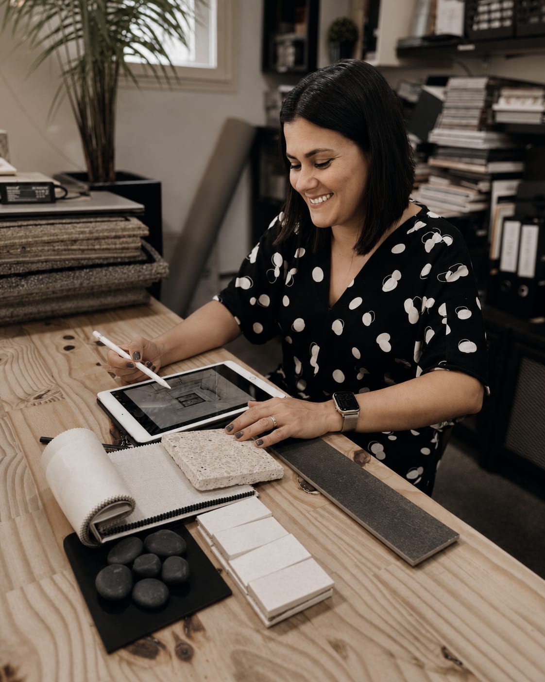 Fabiola de Souza trabalhando no iPad sobre a mesa de amostras de materiais, 2022, acervo INSIDE