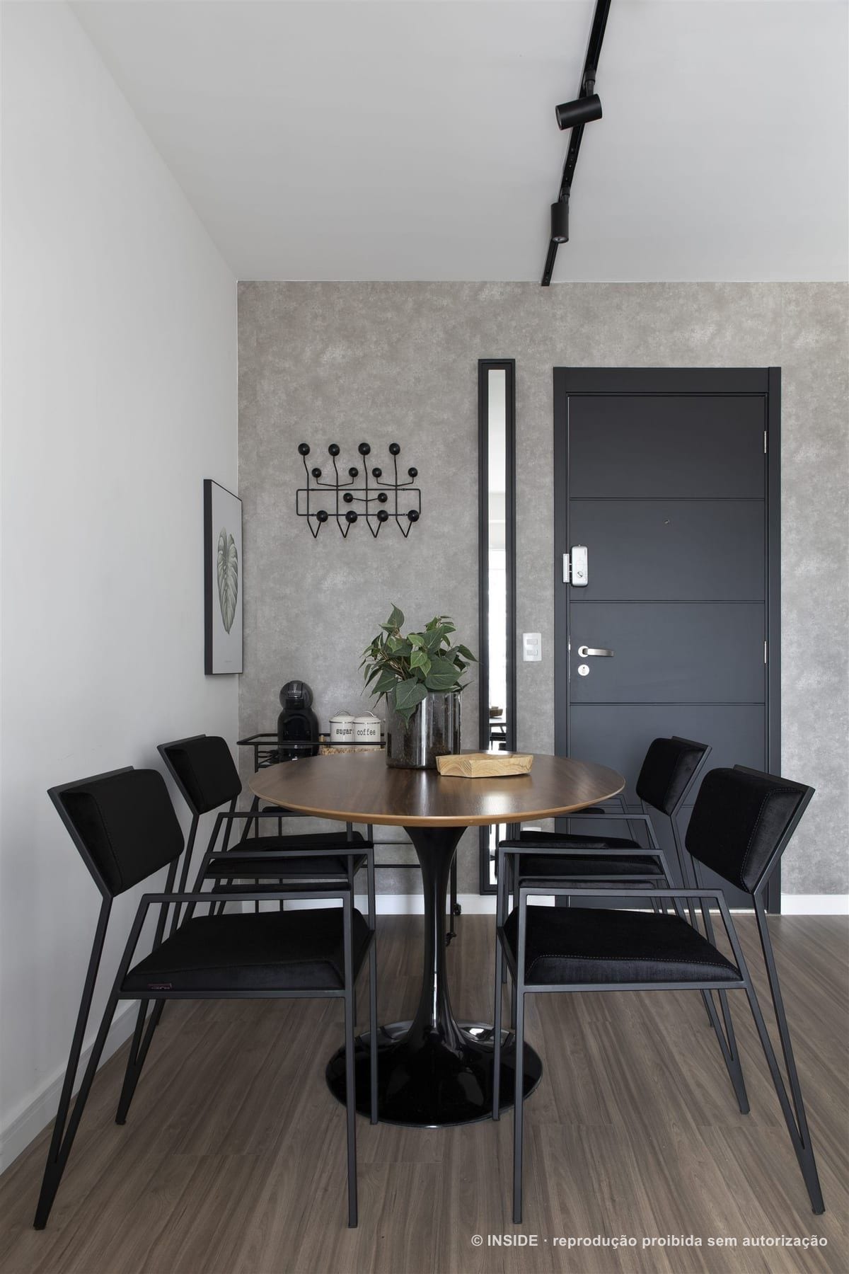 Sala de jantar de apartamento alugado com mesa redonda de madeira, cadeiras pretas e porta grafite, projeto INSIDE