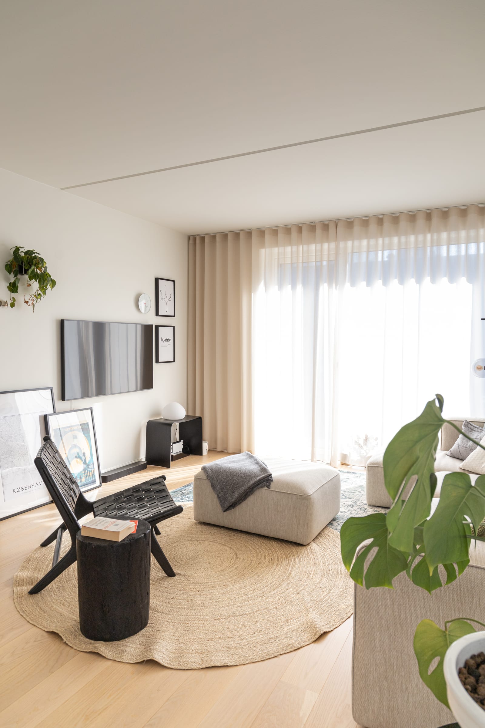 O estar em vertical com tronco preto, pufe e tapete de juta, projeto INSIDE em Copenhague, 2022