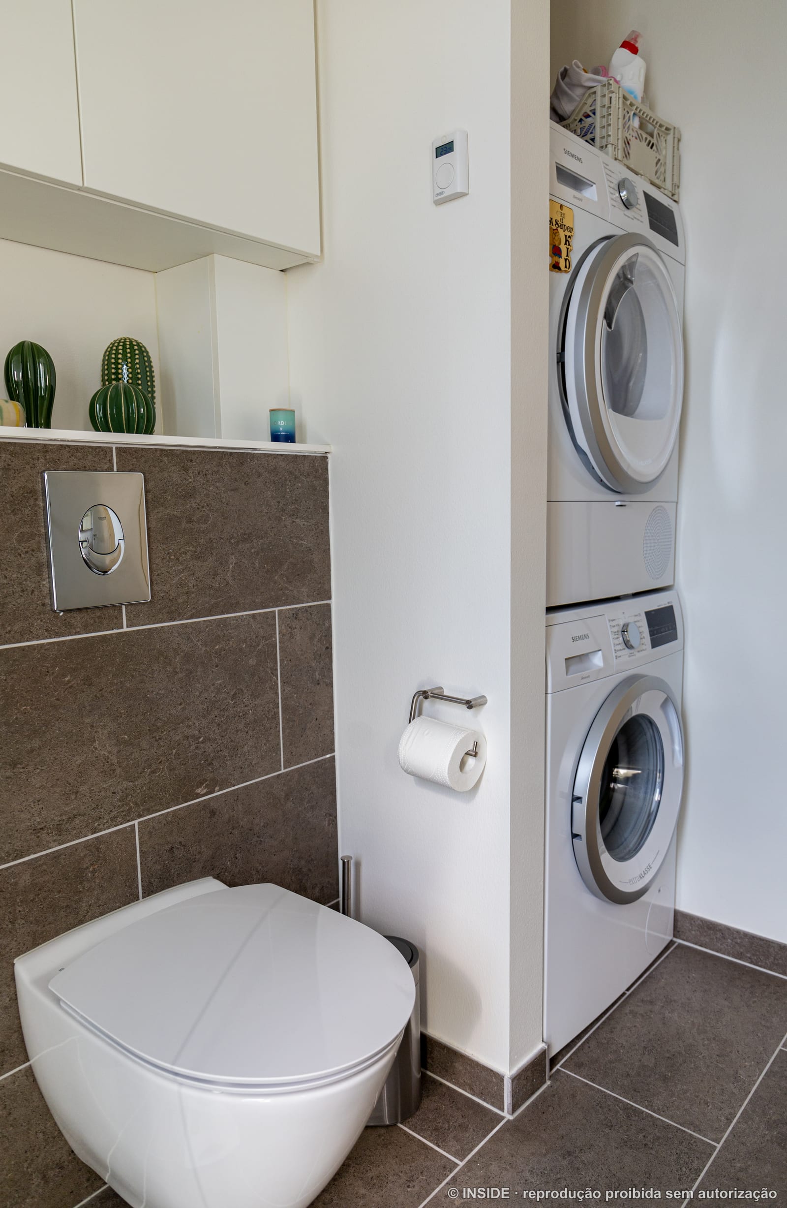Lavanderia compacta com lava e seca empilhadas e porcelanato grafite, projeto INSIDE em Copenhague, 2022