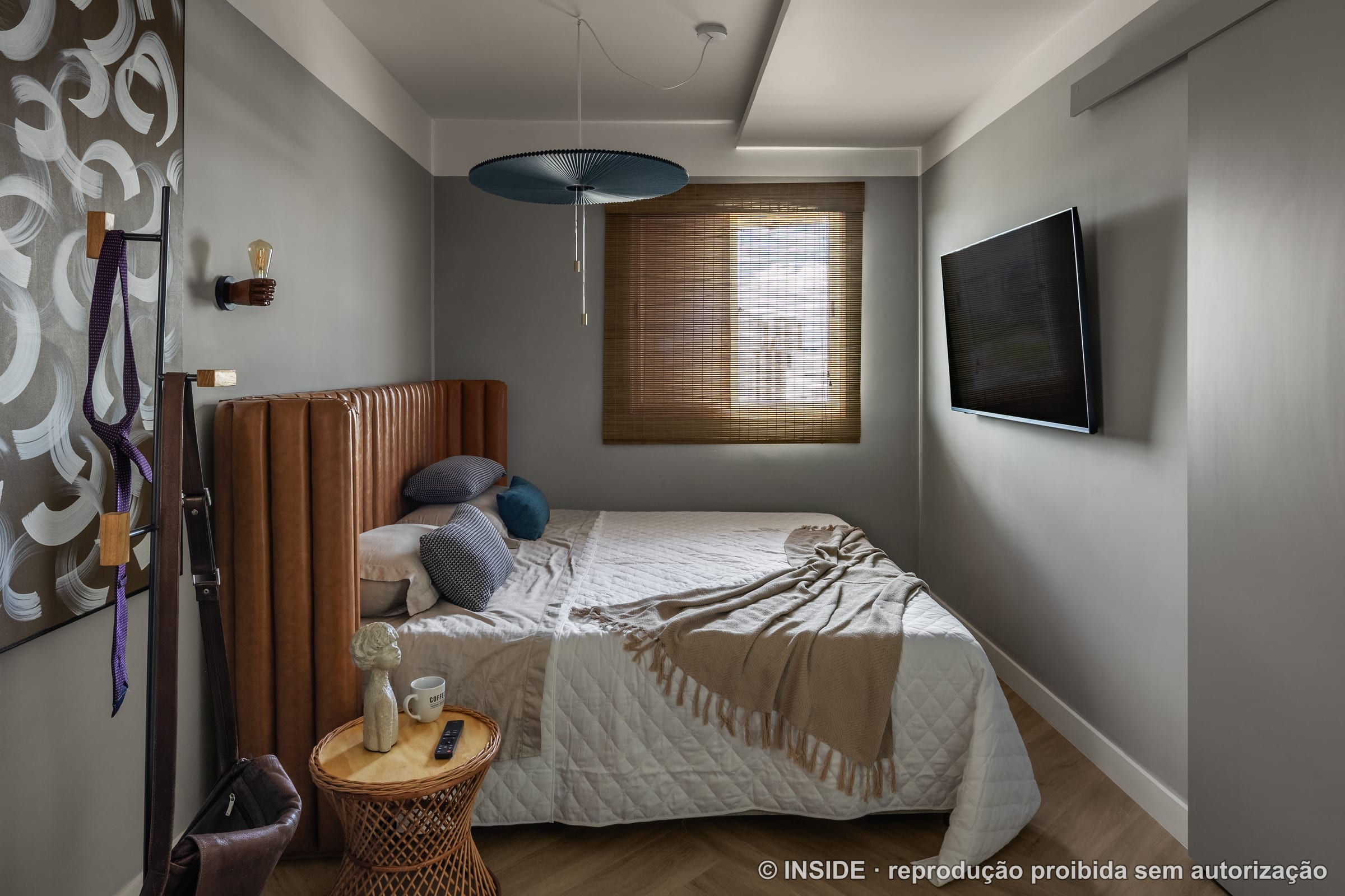 Quarto de casal com cabeceira estofada em couro caramelo canaletado, pendente azul e persiana de bambu, projeto INSIDE