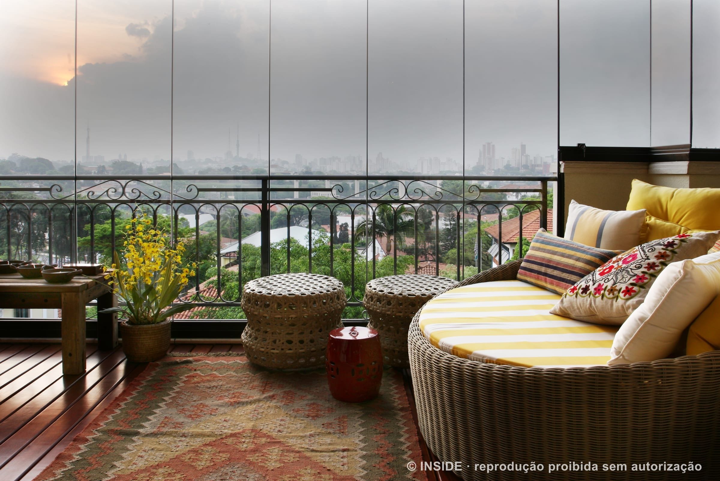 Pacaembu-RA: a varanda envidraçada com o skyline de São Paulo ao fundo, daybed listrado e kilim, acervo INSIDE