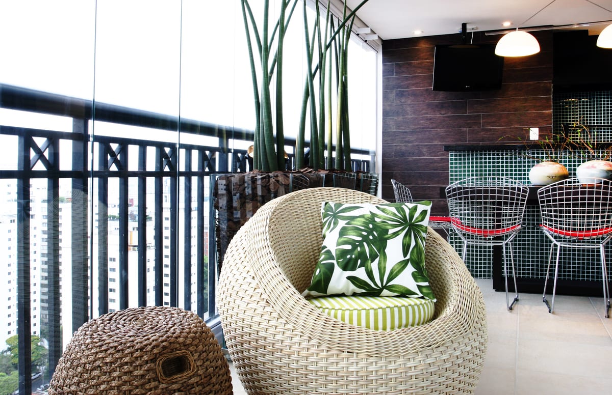 A varanda inteira: sansevierias em canteiro de vidro, poltrona de fibra e a cidade ao fundo. Paisagismo Villa Eco, projeto INSIDE, apartamento da Rua New York, Brooklin